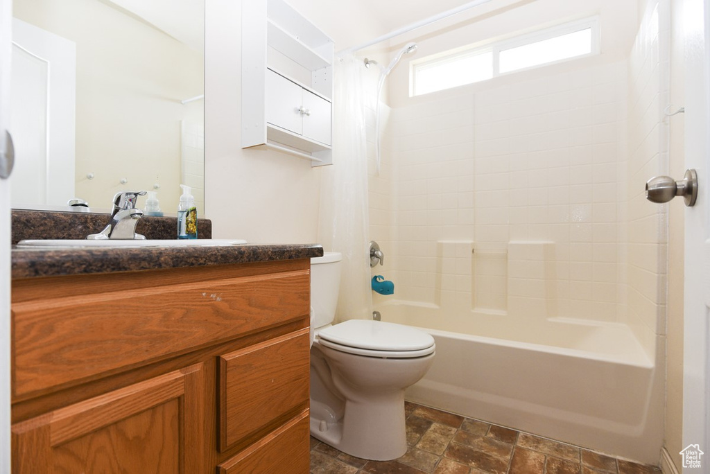 Full bath featuring toilet, vanity, shower / tub combo, and stone finish flooring