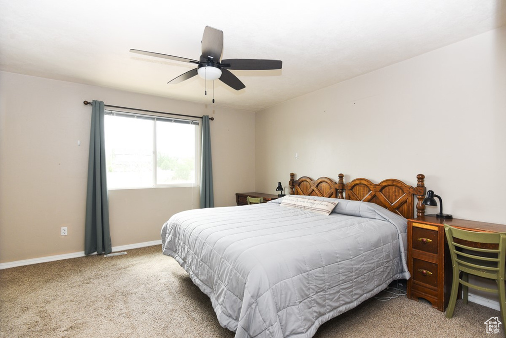 Bedroom with light colored carpet, baseboards, and ceiling fan