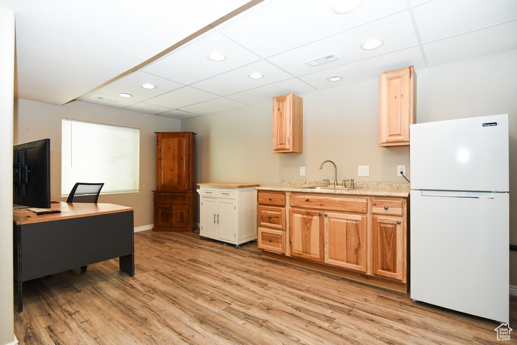 Kitchen featuring freestanding refrigerator, a sink, light wood finished floors, recessed lighting, and baseboards