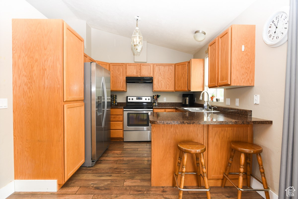 Kitchen with stainless steel appliances, a sink, exhaust hood, a peninsula, and vaulted ceiling