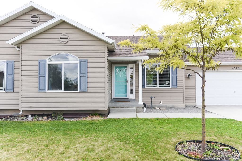 View of front of home featuring a garage, a front yard, concrete driveway, and a shingled roof