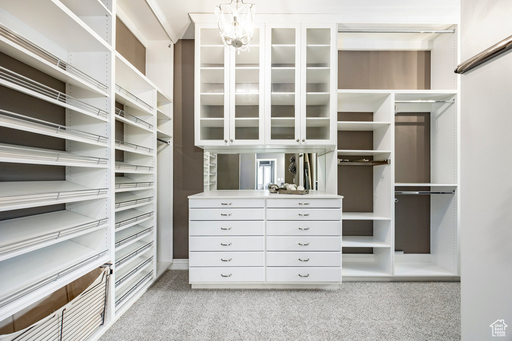 Walk in closet with carpet floors and a chandelier