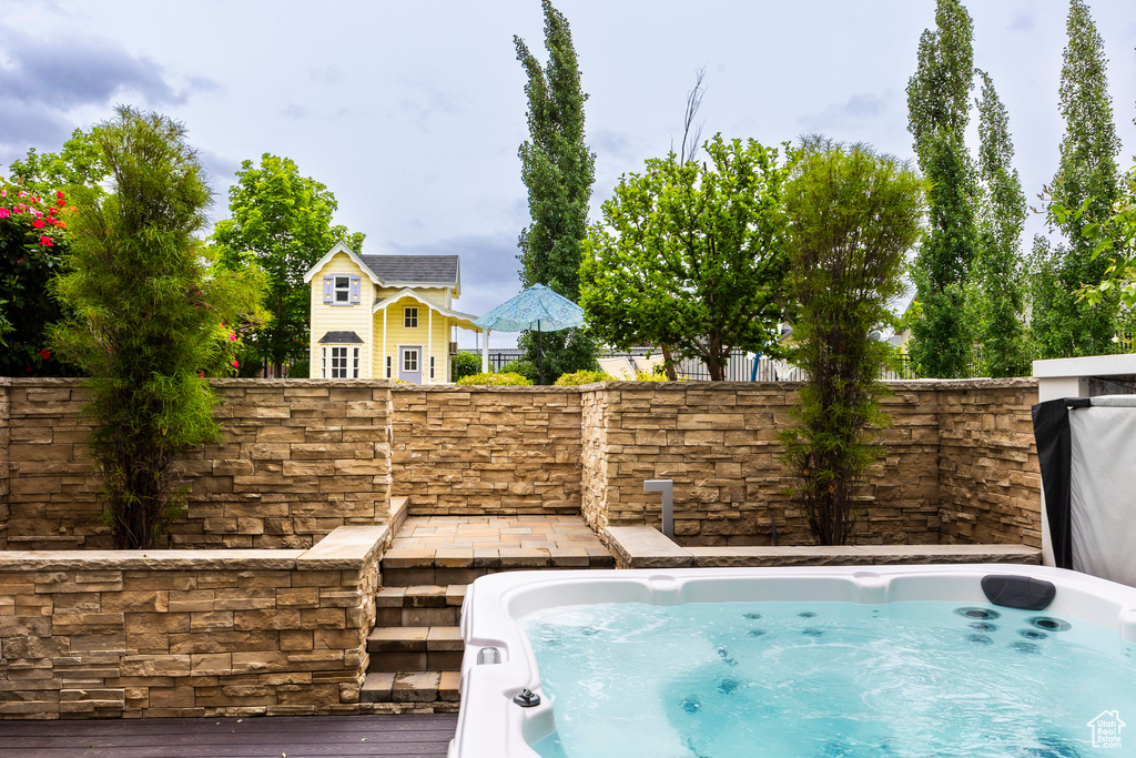 View of swimming pool featuring an outdoor hot tub and fence