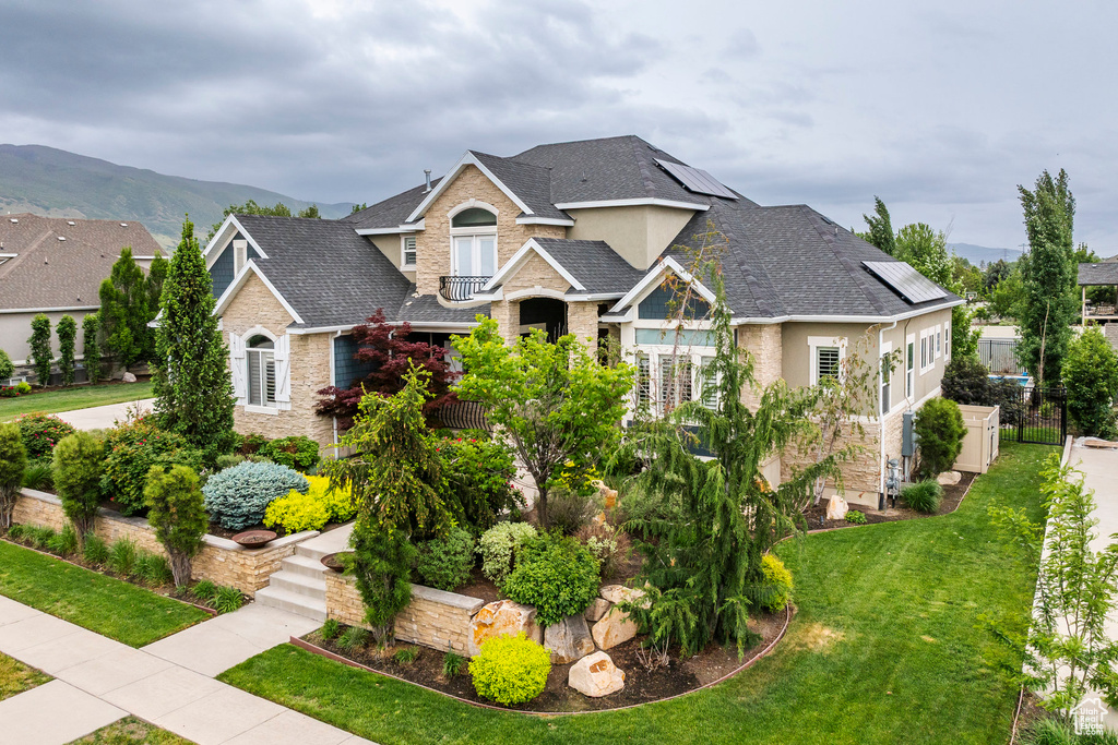Craftsman inspired home with roof mounted solar panels, a front lawn, stucco siding, stone siding, and a shingled roof