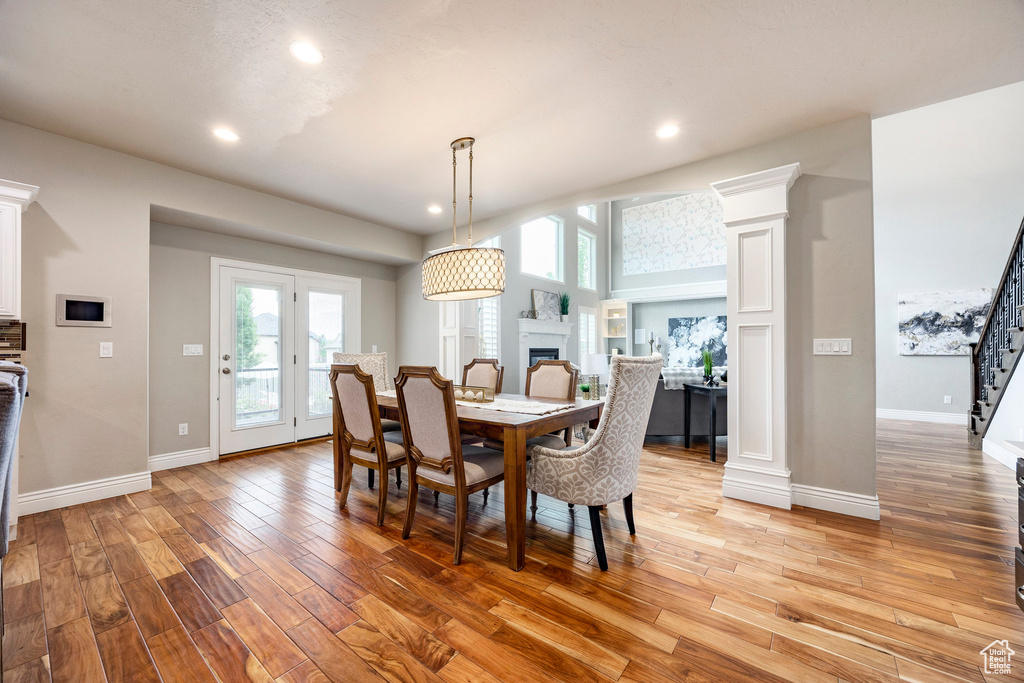 Dining room featuring light wood-style floors, baseboards, a fireplace, recessed lighting, and decorative columns