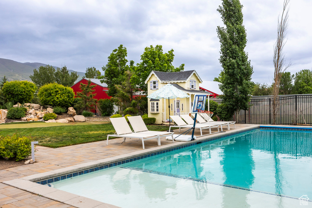 View of pool featuring a storage structure, fence, an outbuilding, and a patio area