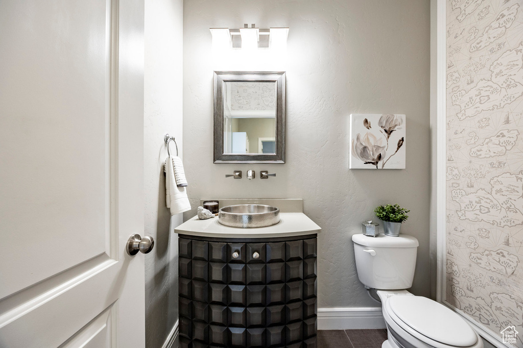 Bathroom with toilet, baseboards, vanity, and tile patterned flooring