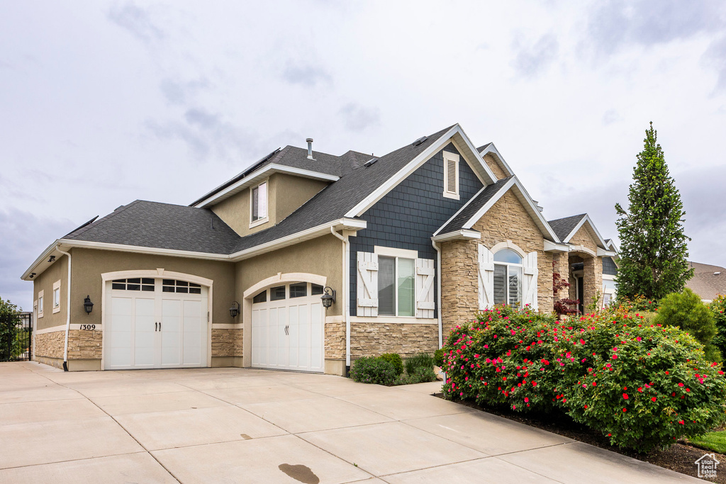 Craftsman inspired home with stone siding, driveway, a garage, stucco siding, and a shingled roof