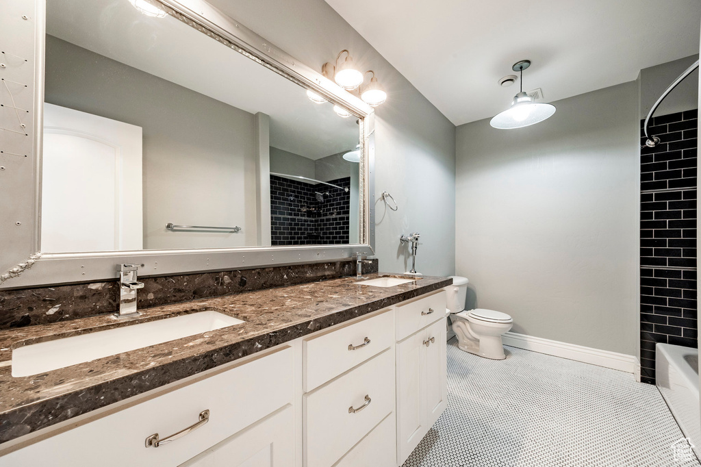 Full bath featuring toilet, double vanity, baseboards, and shower / tub combination