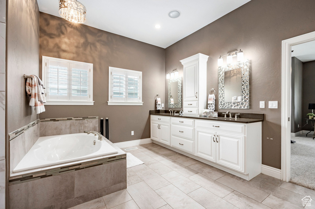 Bathroom featuring a garden tub, double vanity, and baseboards