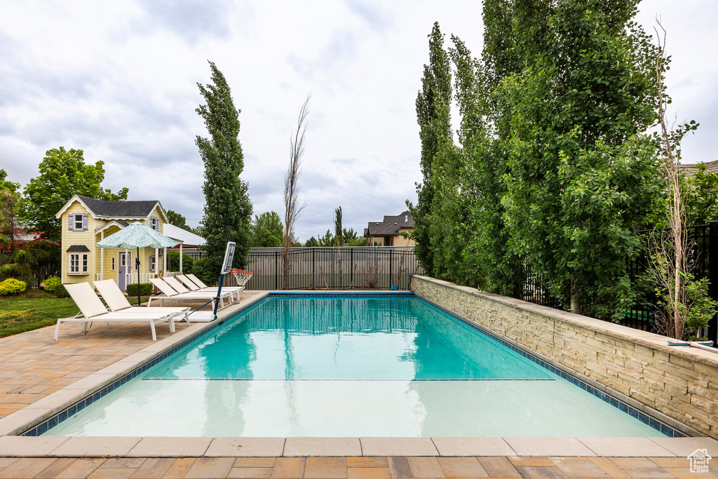 View of swimming pool featuring a patio area, an exterior structure, fence, and an outbuilding