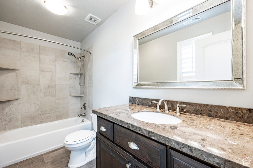 Bathroom with toilet, vanity, and  shower combination