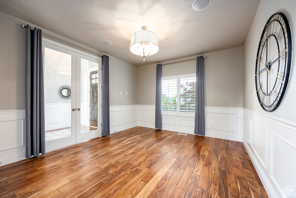 Spare room with french doors, wood finished floors, a wainscoted wall, and a decorative wall