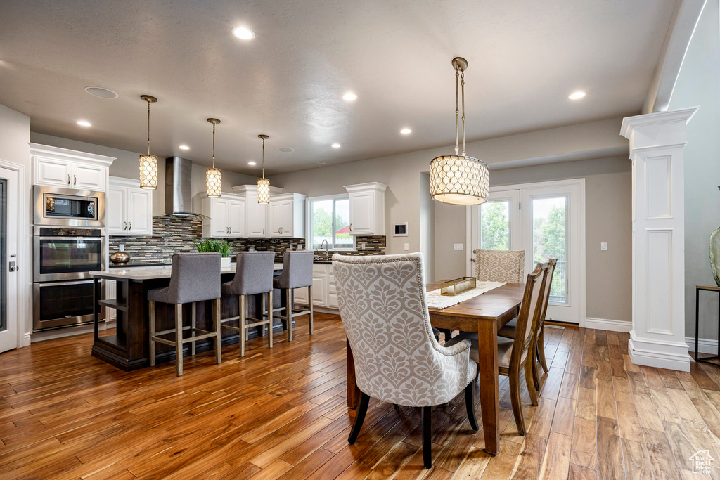 Dining area with wood-type flooring, recessed lighting, baseboards, and decorative columns