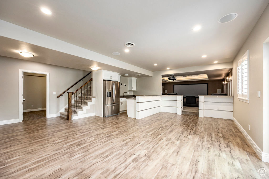Unfurnished living room with stairway, light wood-type flooring, baseboards, and recessed lighting