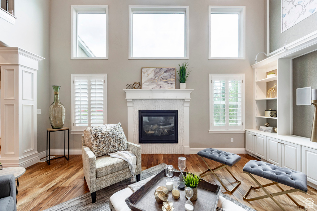 Living area featuring a towering ceiling, a glass covered fireplace, light wood finished floors, and baseboards