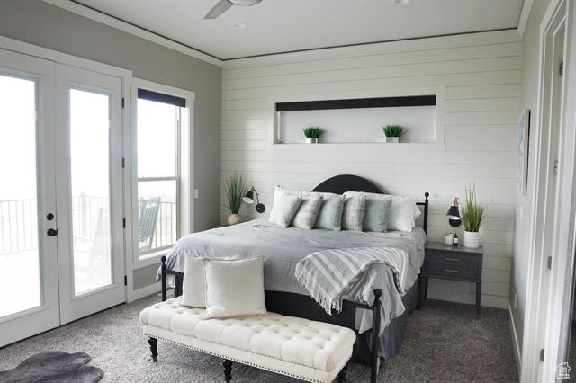 Carpeted bedroom with multiple windows, access to exterior, french doors, ornamental molding, and wood walls