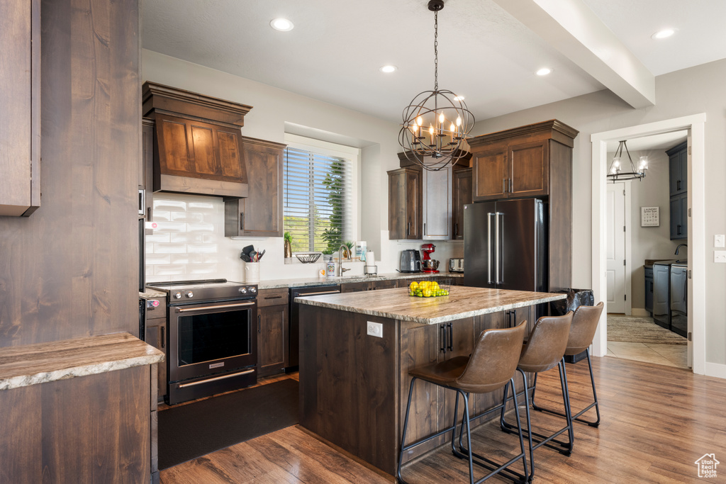 Kitchen with stainless steel appliances, a chandelier, a center island, a kitchen breakfast bar, and recessed lighting