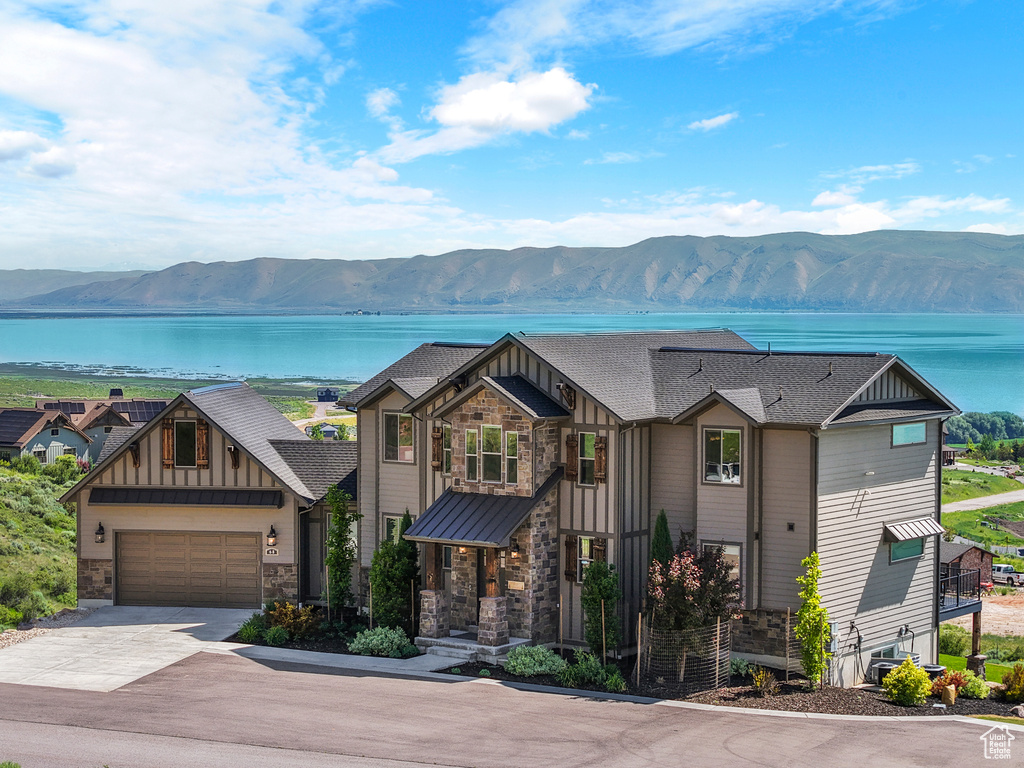 Craftsman-style house with board and batten siding, a water and mountain view, stone siding, and concrete driveway