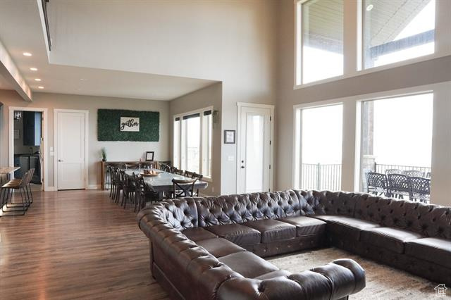 Living area with a high ceiling, wood finished floors, healthy amount of natural light, recessed lighting, and baseboards
