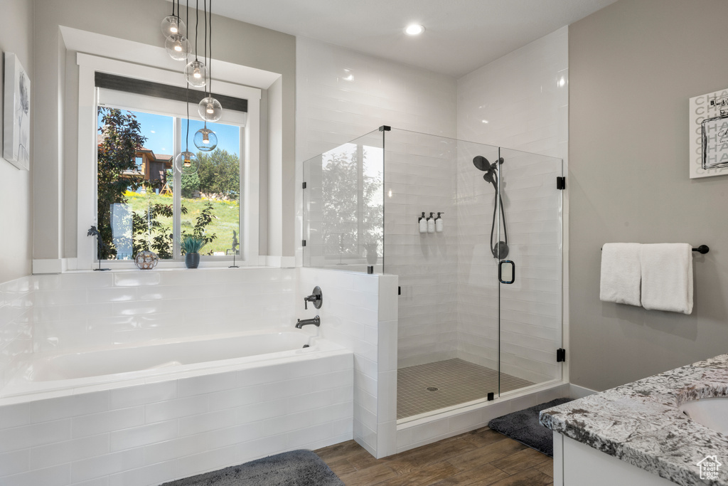 Full bathroom with a garden tub, vanity, wood finished floors, and a stall shower
