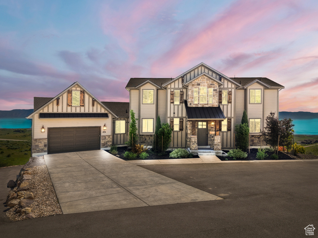 View of front facade with stone siding, board and batten siding, concrete driveway, and a garage