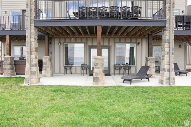 Rear view of house featuring a patio, a balcony, and a lawn