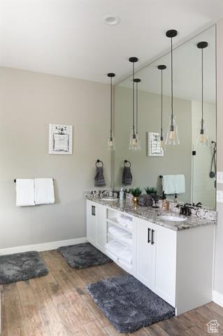 Full bath featuring wood finished floors, double vanity, and baseboards