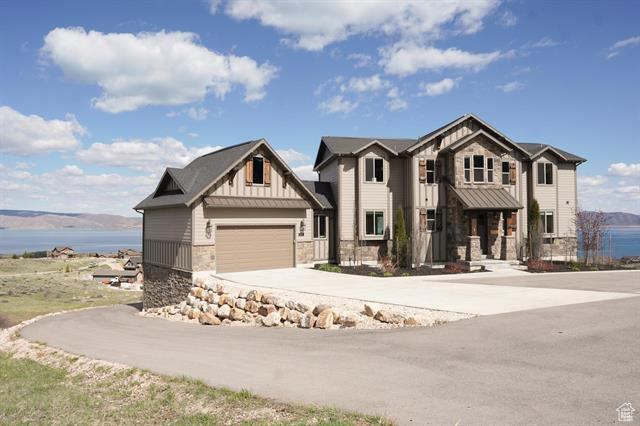 Craftsman house with stone siding, driveway, board and batten siding, and a water view