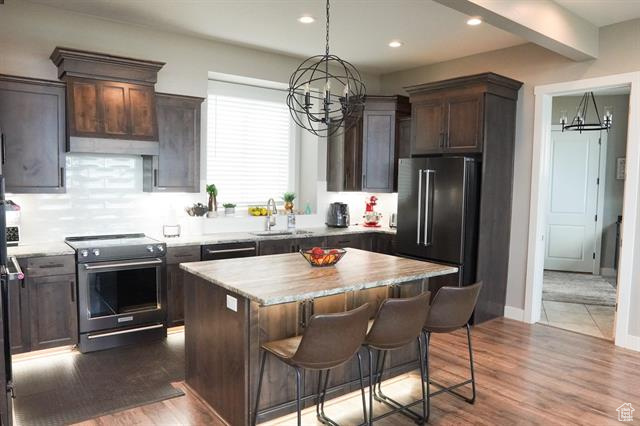 Kitchen featuring stainless steel electric range, a sink, a chandelier, dark brown cabinets, and recessed lighting