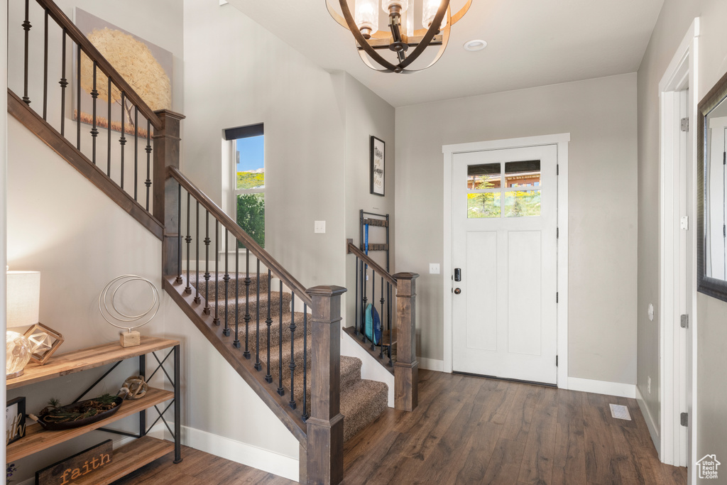 Foyer entrance featuring a chandelier, wood finished floors, and stairway