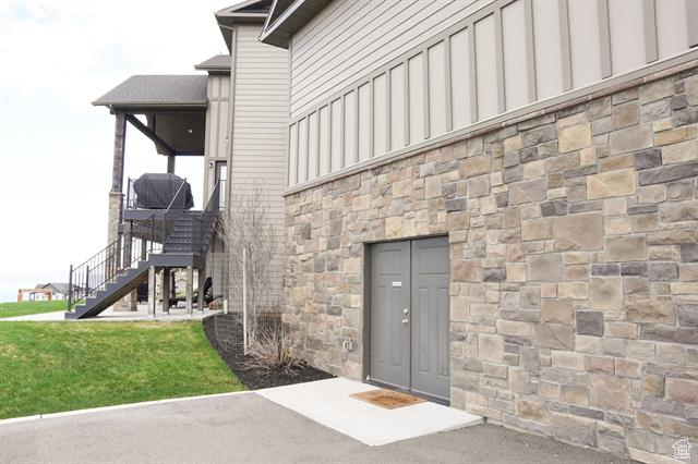 View of exterior entry with board and batten siding, stone siding, and a yard