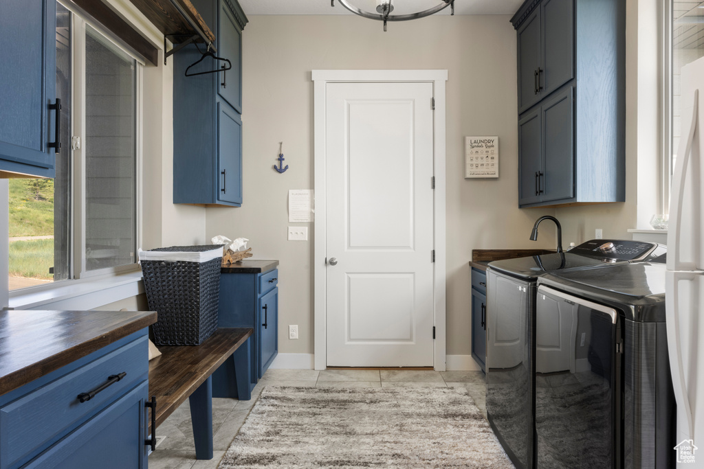 Laundry room with independent washer and dryer, cabinet space, and light tile patterned floors