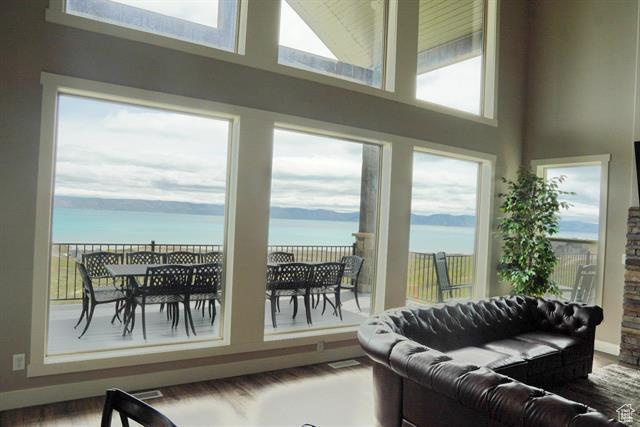 Living area featuring a towering ceiling, a water view, and wood finished floors