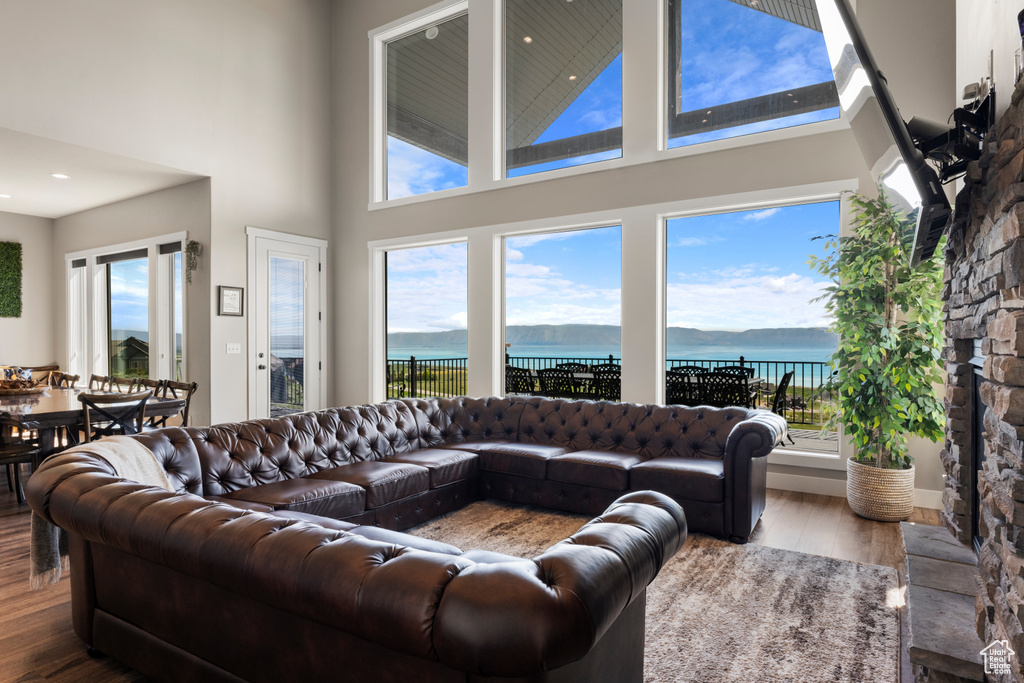 Living area with a towering ceiling, wood finished floors, a water view, and healthy amount of natural light