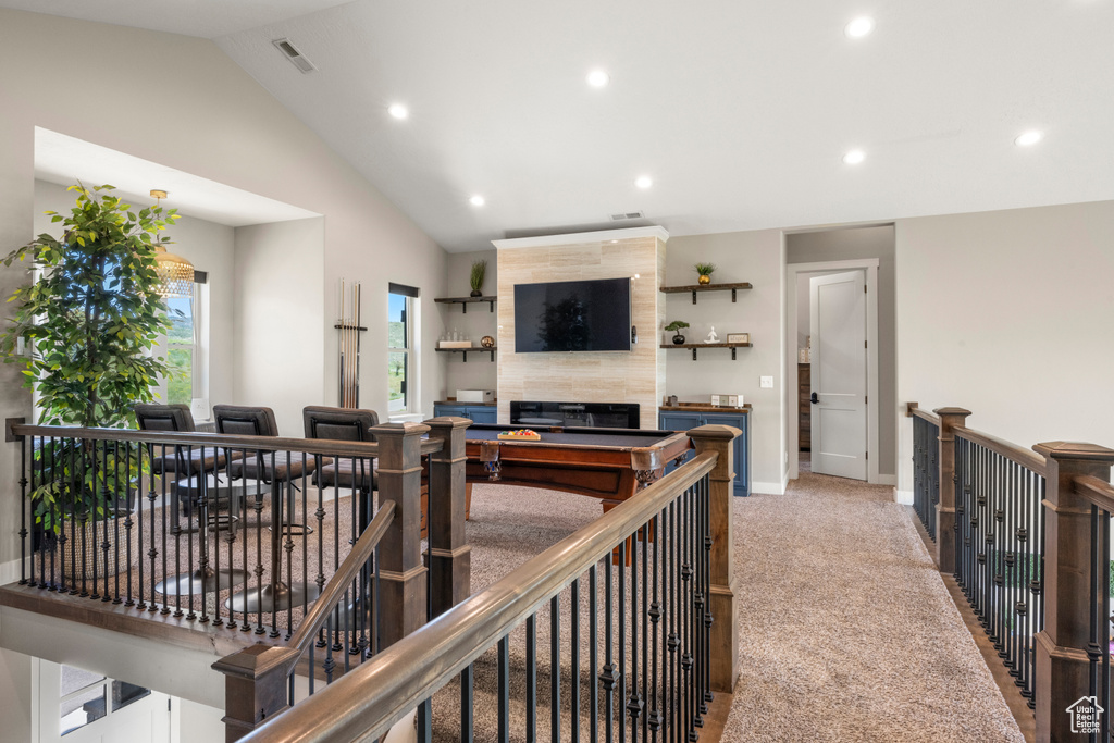 Living area featuring a tile fireplace, recessed lighting, lofted ceiling, and light carpet