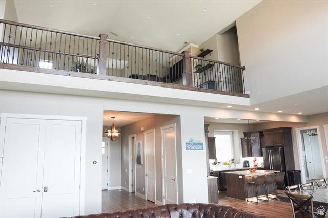 Living room featuring a chandelier, a towering ceiling, dark wood-style floors, and recessed lighting