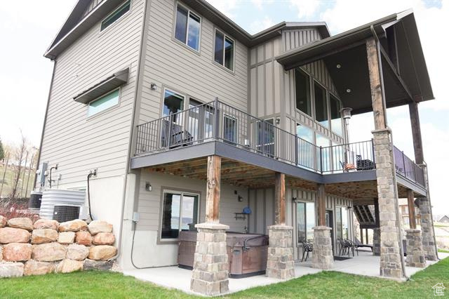 Back of property featuring a balcony, a patio, board and batten siding, and a yard