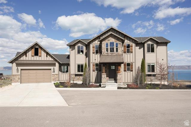 View of front of home with stone siding, board and batten siding, driveway, and an attached garage