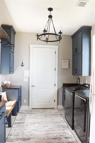 Laundry room with cabinet space, independent washer and dryer, a chandelier, and baseboards