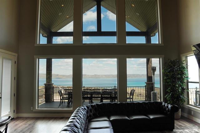 Living area with a water view, wood finished floors, a towering ceiling, and baseboards