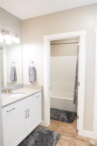 Full bath featuring wood finished floors, vanity, shower / bathtub combination with curtain, and baseboards