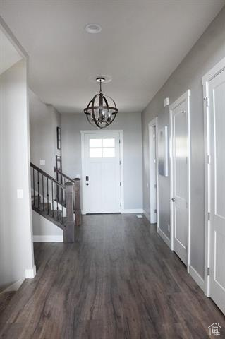 Foyer featuring baseboards, wood finished floors, a chandelier, and stairway