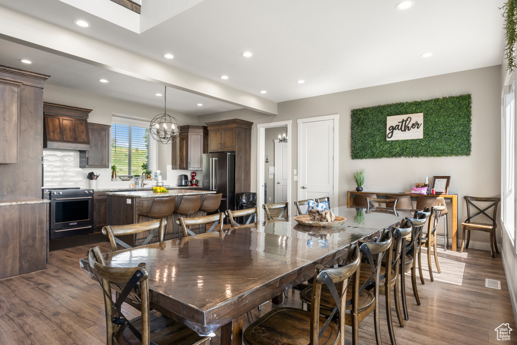 Dining space with dark wood-type flooring, recessed lighting, and a chandelier