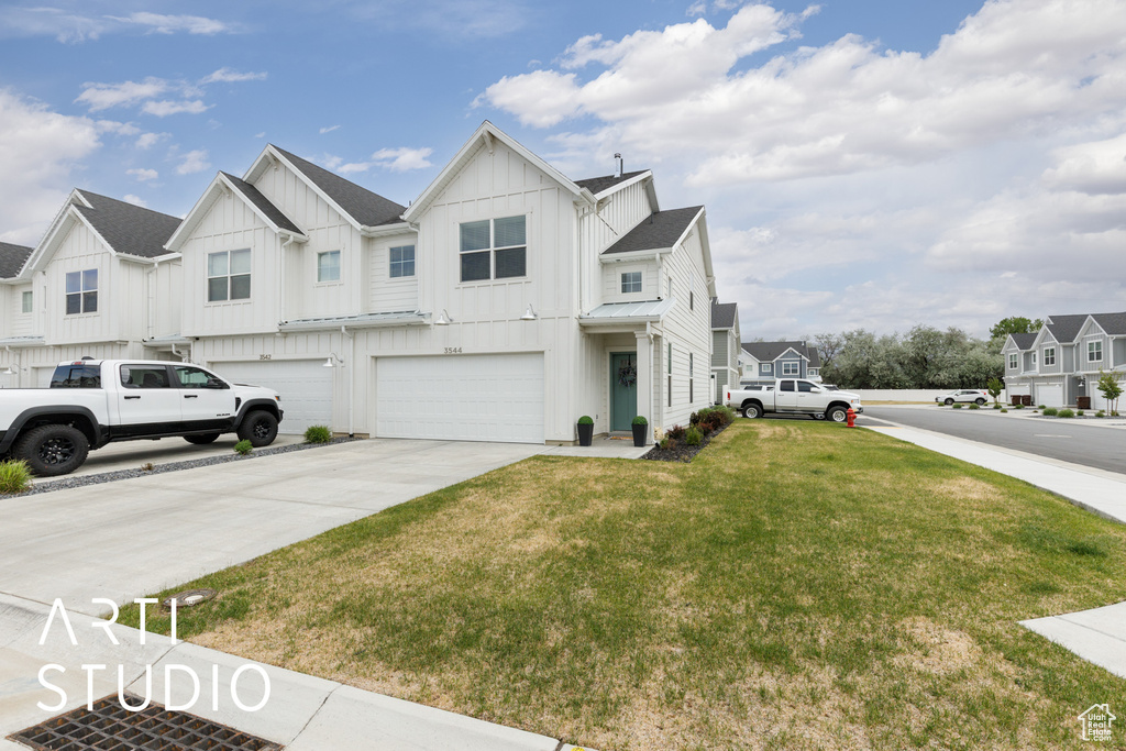 View of front of house with board and batten siding, a garage, a front yard, driveway, and a residential view