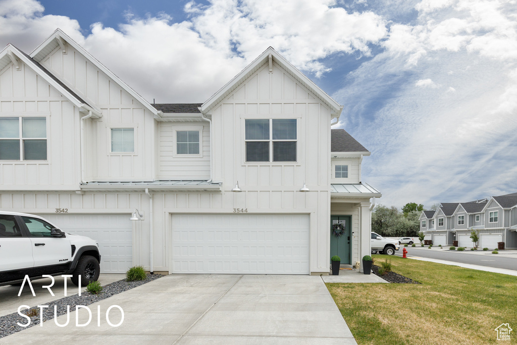 View of front of home with board and batten siding, a garage, concrete driveway, a front lawn, and a shingled roof