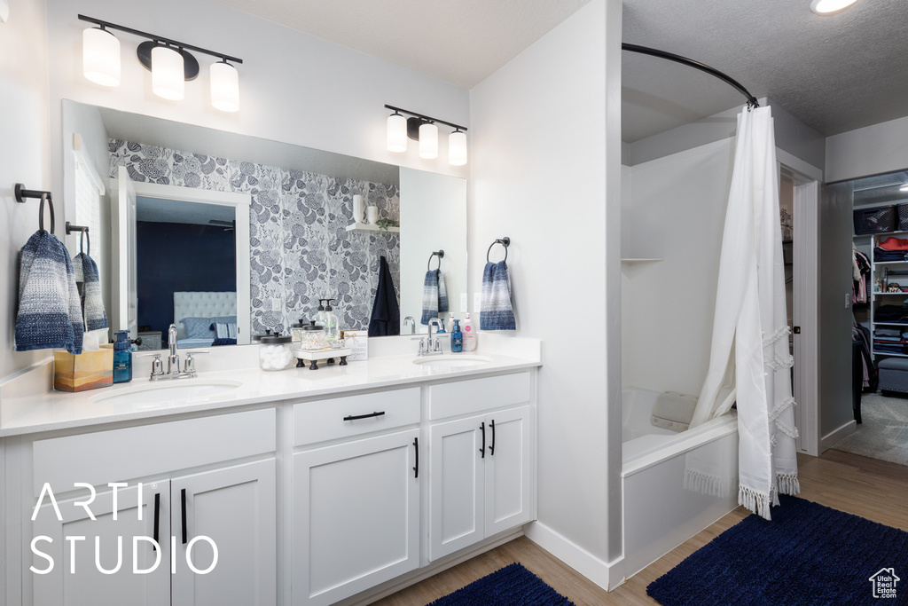 Full bath with wood finished floors, double vanity, shower / bath combo, and ensuite bathroom