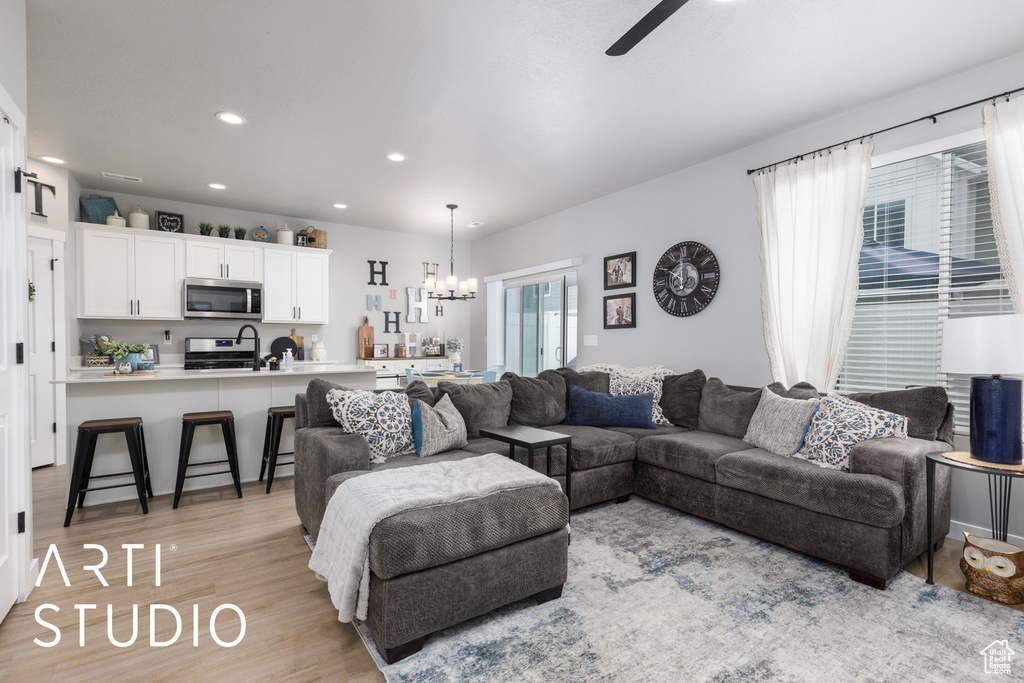 Living room with a chandelier, light wood-style flooring, ceiling fan, and recessed lighting