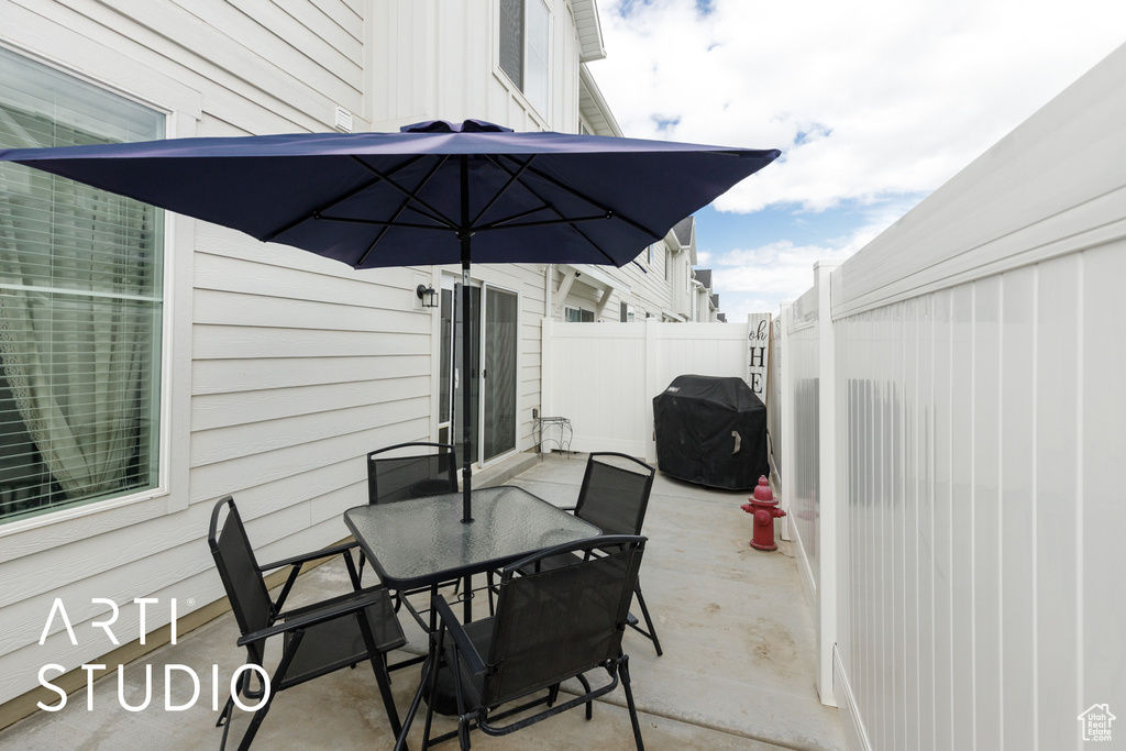 View of patio with fence, outdoor dining area, and grilling area
