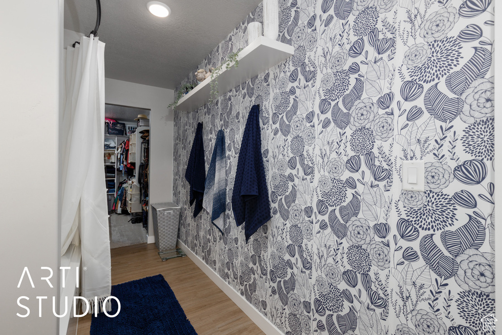 Bathroom with wood finished floors, baseboards, and wallpapered walls